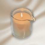 Massage candle in a clear glass holder on a white background