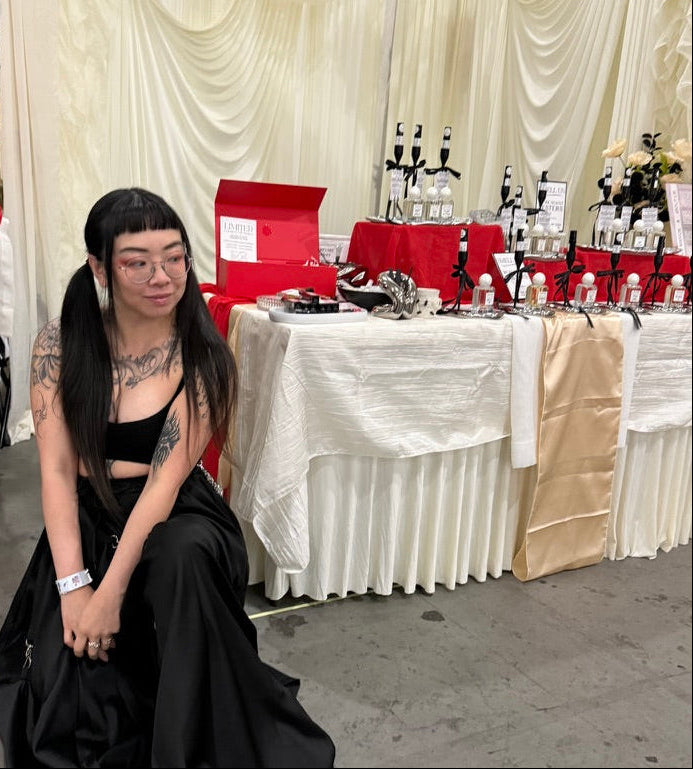 Person in a black dress sitting on the floor with a decorated table in the background