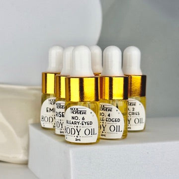 Six small gold bottles on a white platform in front of a white background